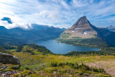 Hidden Lake and pyramid-shaped Bearhat Mountain in Glacier National Park, Montana, USA. Early morning light and scattered clouds above alpine valley in American Rockies. Hiking in Rocky Mountains. clipart