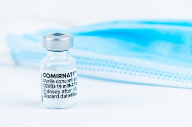 Celadna, Çek Cumhuriyeti - 05.30.2021: Beyaz arka planda Pfizer tarafından yapılan Comirnaty Aşısı, yanında mavi maske