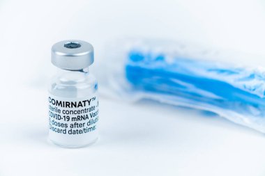 Celadna, Czechia - 05.30.2021: Pfizer 'ın Comirnaty aşısı beyaz zemin üzerinde, yanında plastik ambalajda mavi şırınga ile