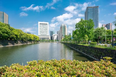 Tokyo, Japonya - 12.05.2019: İmparator Sarayı kompleksinin su kanalı ve taş duvarı İwaida Köprüsü 'nden izlendi. Gökdelenler suya yansıyor