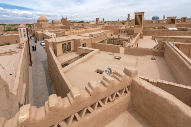 Yazd, İran - 14.04.2019: Sıcak bir günde şehrin tarihi bölümünün kil binaları ve rüzgar yakalayıcı kuleleri ile çatılarının manzarası