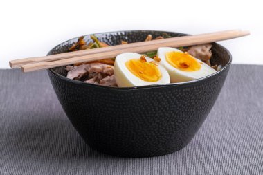 Kaynamış yumurta, sebze ve hindi buluşması ile birlikte ramen eriştesi. Kaynayan et suyuyla doldurulmaya hazır. Tahta çubuklar. Yeni hazırlanmış ve güzel görünümlü Asya yemekleri..