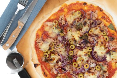 Beyaz arka planda izole edilmiş, fırından yeni çıkmış pizza al tono 'sunun en iyi görüntüsü. Mavi kumaş, pizza dilimleyici ve çatal bıçak takımı..