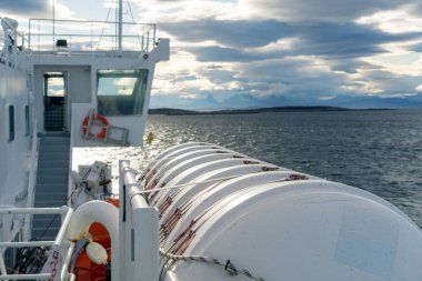 Lofoten Adaları 'nda denizde yelken açan bir tekneye bağlı büyük beyaz bir tank. Uzak ufuktaki dramatik bulutlar ve sıradağlar.