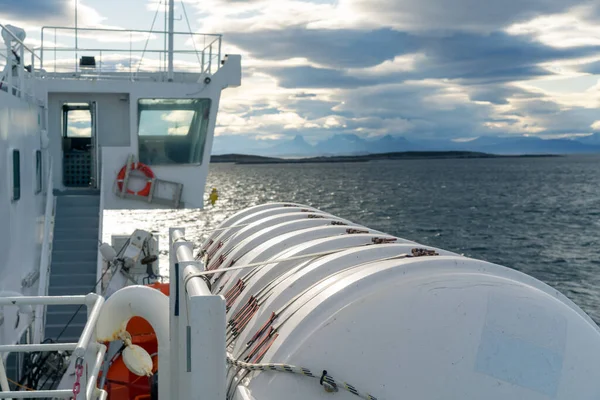 Lofoten Adaları 'nda denizde yelken açan bir tekneye bağlı büyük beyaz bir tank. Uzak ufuktaki dramatik bulutlar ve sıradağlar.