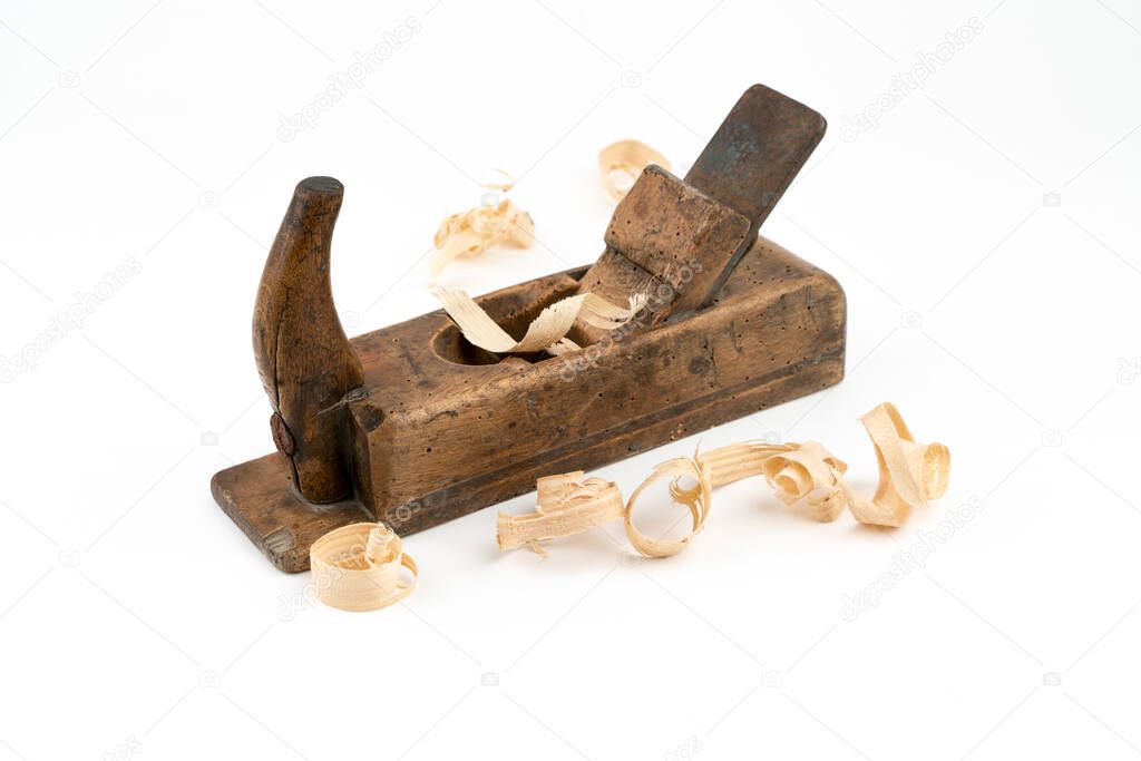 Horizontal high angle angle studio shot of small vintage wood planer isolated on white background. Old carpenter tool with wood worm holes in it. Thin wooden shavings. Carpentry concept.