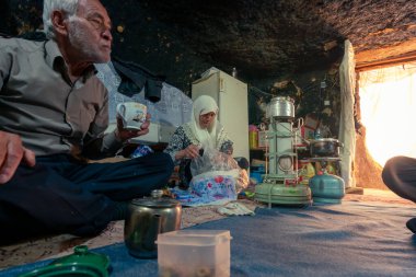 Mahan, İran - 04.09.2019: Yaşlı İranlı çift, mütevazı mağaralarındaki evlerinde akşam yemeği için hazırlanıyorlar.