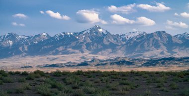 İran çölünün tepesinde karlı dağlar yükseliyor. Antik İran 'da güneşli bir günde yumuşak bir sis içinde görkemli dört binlikler..