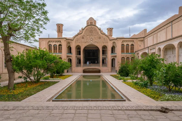 Kashan, Irão - 04.19.2019: Pátio da ricamente decorada Casa Borujerdi, famosa casa histórica da era Qajar. Piscina, torres de vento, pequeno jardim persa. — Fotografia de Stock