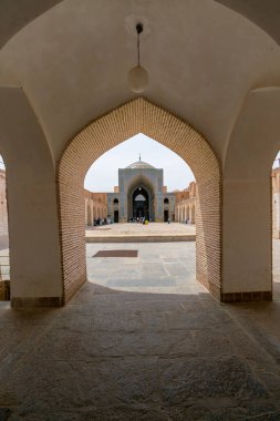 Yazd, İran - 13.04.2019: Altıgen ve turkuaz fayanslarıyla tarihi Jameh Camii 'nin avlusu. İnsanlar Şii camiinin bahçesinde yürüyorlar..