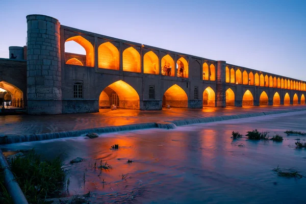 Isfahán, Irán - 14.04.2019: Atardecer en el puente Si O Se Pol, Isfahán, Irán. Luces naranjas en el puente contrastan con el cielo azul desvanecido. — Foto de Stock