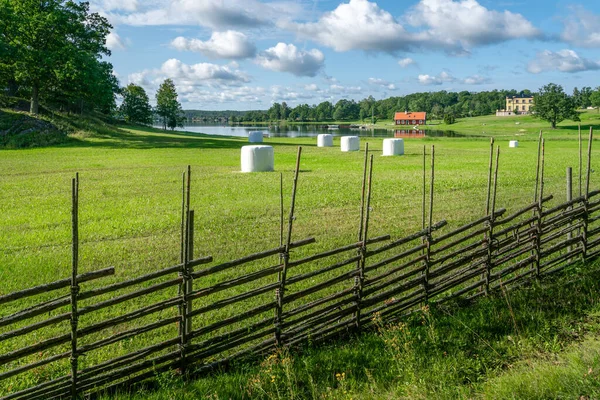 Small settlement farm in sourthern Sweden on a beautiful sunny summer day. Holiday in Swedish countryside. Vintage fence and white heystacks. — Stock Photo, Image