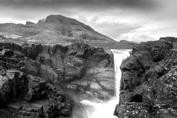 Close-up, largo, preto e branco tiro de ângulo baixo do poderoso Stuor Muorkkegarttje cachoeira no rio Lulealven em um dia parcialmente nublado de verão ártico. Stora Sjofallet National Park, Suécia. — Fotografia de Stock