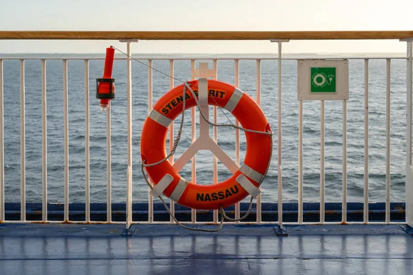 Karlskrona, Suecia - 08.14.2021: Boya salvavidas anaranjada unida a la barandilla a bordo del barco Stena Spirit con el mar Báltico en el fondo. — Foto de Stock
