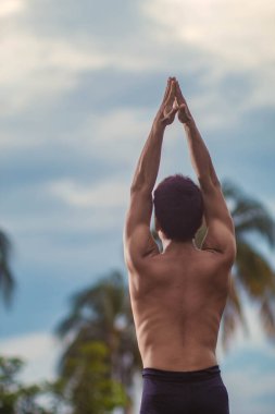 Genç Latin adam gün batımında yoga yapıyor.