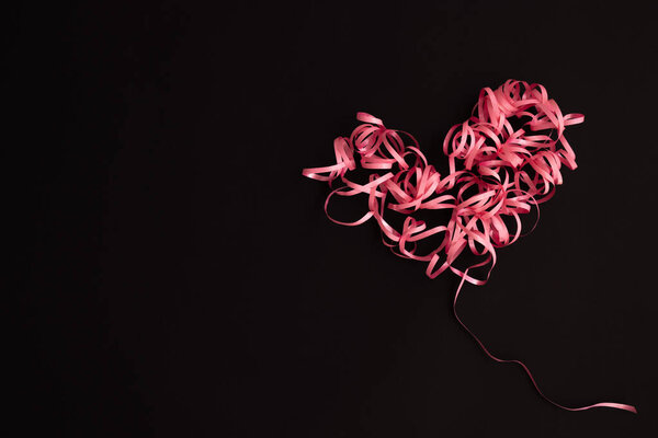 Heart made of ribbon on a black with copy space. Love concept.
