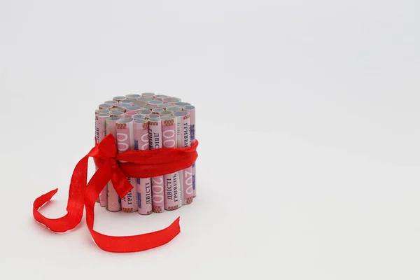 200 gryvnias en un rollo con una cinta de regalo roja. En un blanco con espacio para el texto — Foto de Stock