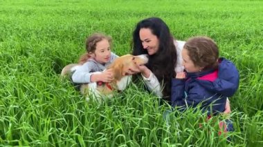 4k Anne ve kızları ve köpekleri çimlerin üzerinde oturuyorlar..