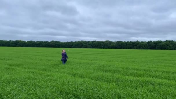 4k Klein meisje springen en gooit gras op een veld. — Stockvideo