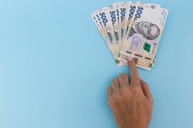 Paraya parmak basıyorsun. Ukrayna Hryvnia 'sı. Mavi bir arkaplanda.