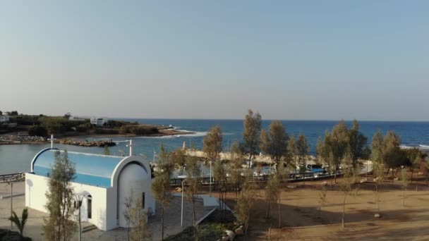 4k Вид с воздуха на церковь в греческом стиле, пирс с лодками и синее море. — стоковое видео