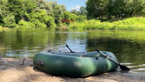 Zielona gumowa łódź stojąca na piaszczystej plaży rzeki. — Wideo stockowe