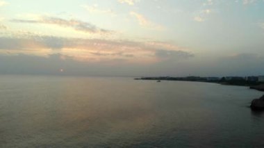 4k Kıbrıs 'ta sakin, yansıtan deniz, gün batımı, insansız hava aracı atışı.