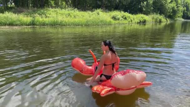 4k乘充气红龙虾在河上漂流的女孩. — 图库视频影像