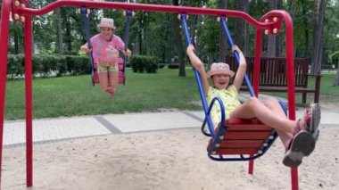 4k Neşeli ikiz kardeşler salıncakta sallanıyor.