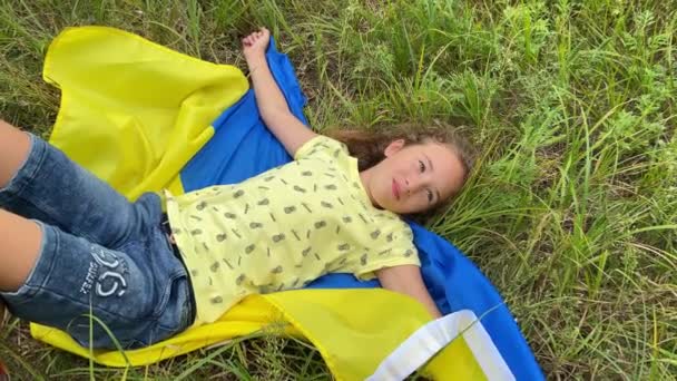4k笑顔小さな女の子は牧草地でウクライナの旗にあります — ストック動画