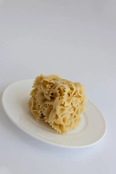 Μαγειρεμένα farfallini ζυμαρικά σε σχήμα κύβου σε λευκό πιάτο. — Φωτογραφία Αρχείου