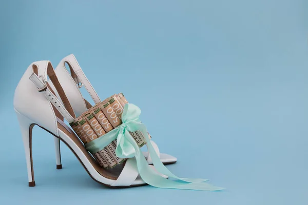 Frauen hohe Schuhe mit weißem Absatz und ukrainischem Geld, gebunden mit einem Geschenkband. — Stockfoto