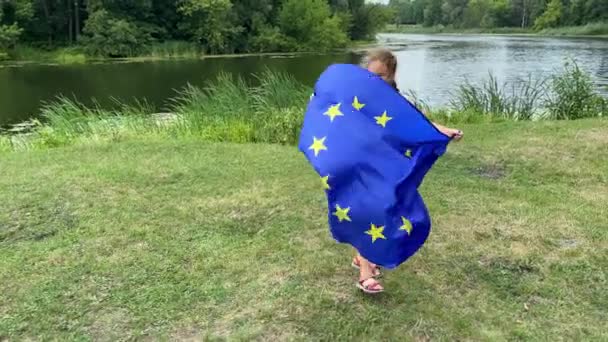 4k Twin flickor har roligt på gräsmattan med ukrainska och Europeiska unionens flaggor. — Stockvideo