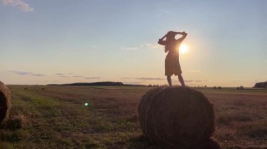 4k Siluet bir kadın saman yığını üzerinde güneş ışığına karşı.