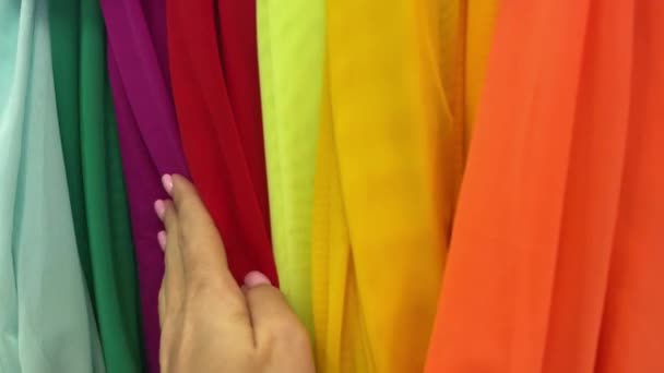 4k Flerfärgat tyg i textilbutik. Kvinnlig hand vidrör tygerna. — Stockvideo