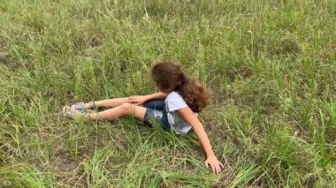 4K Küçük kız düştükten sonra ayağa kalktı. Kız düştükten sonra bacağına bakıyor..