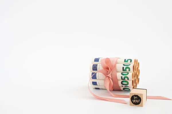 50 euro w rolkach związanych z różową wstążką i sześcianem ze słowami. — Zdjęcie stockowe