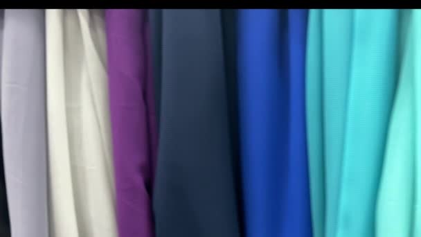 4k Multicoloured fabric in a textile shop. Female hand touches the fabrics. — Stock Video