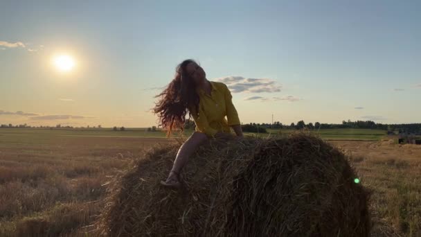 4k fille balançant sur une botte de foin roulée, secouant les cheveux et dansant. — Video