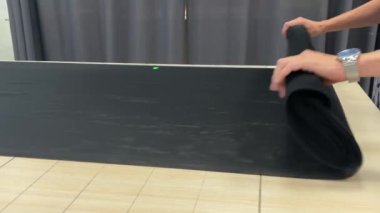 4k Erkek Elleri Tekstil dükkanındaki bir masanın üzerindeki siyah kumaş örgüsünü büker.