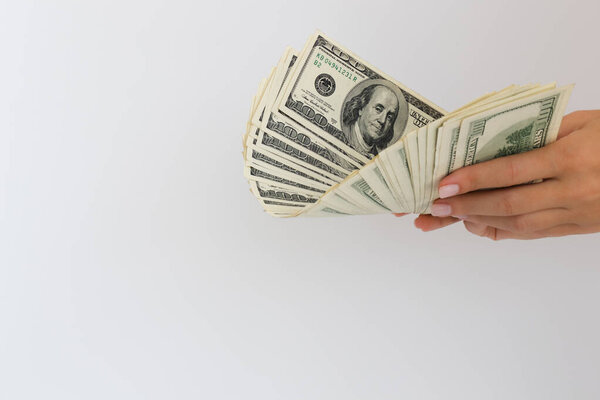 Руки женщины держат доллары США. На белом фоне с копировальным пространством.