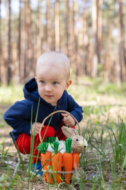 Paskalya sepetiyle parkta oturan küçük bir çocuğun portresi.