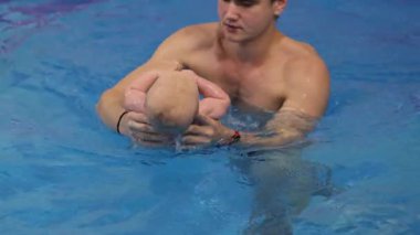 Bebek koçla yüzerken oyuncak çiğniyor. Yeni doğan için yüzüyorum. 4k görüntü
