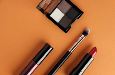 Turuncu arka planda makyaj malzemesi seti. Genel kozmetik ürün illüstrasyonu.