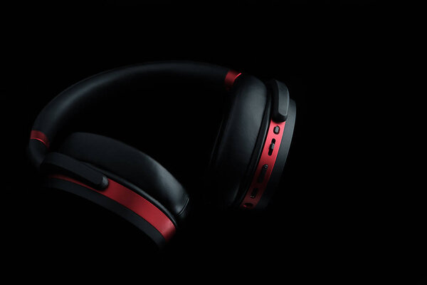 Черные и красные наушники на черном. Музыкальные технологии.