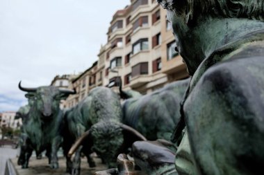 Pamplona boğası arkasında bina olan bir anıt işletiyor. Ön planda koşucu. İspanya tatili.