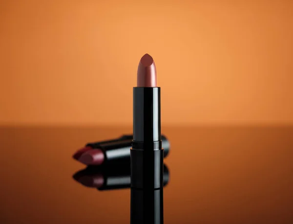 Turuncu yansıtıcı yüzeyde ruj izi var. Minimalizm kozmetik.