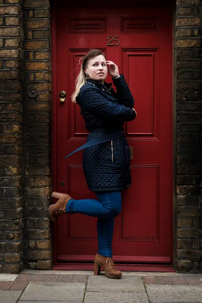 Hermosa Mujer Rubia Posando Contra Una Puerta Roja —  Fotos de Stock