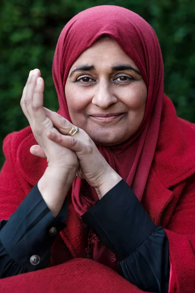 Mature muslim woman wearing hijab is posing and looking to camera.