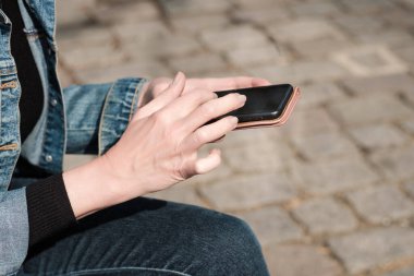Akıllı telefon kullanan eller. Yakın plan. Denim kıyafeti..